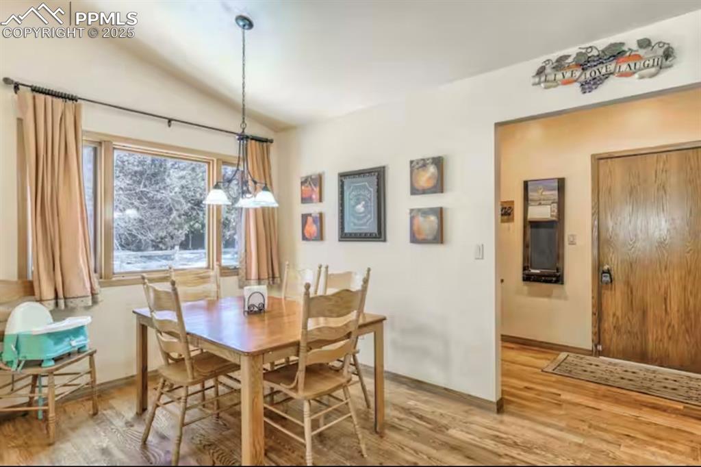 Image 12 of 48: Dining room with light wood-style floors and lofted ceiling