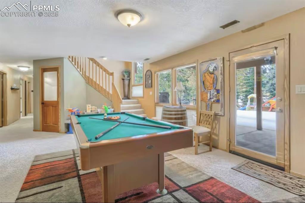 Image 27 of 48: Recreation room with pool table, carpet flooring, and a textured ceiling