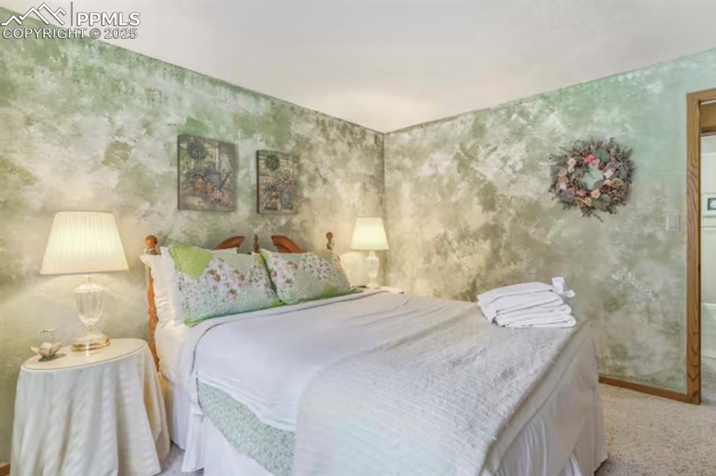 Image 32 of 48: Bedroom featuring wallpapered walls and light carpet