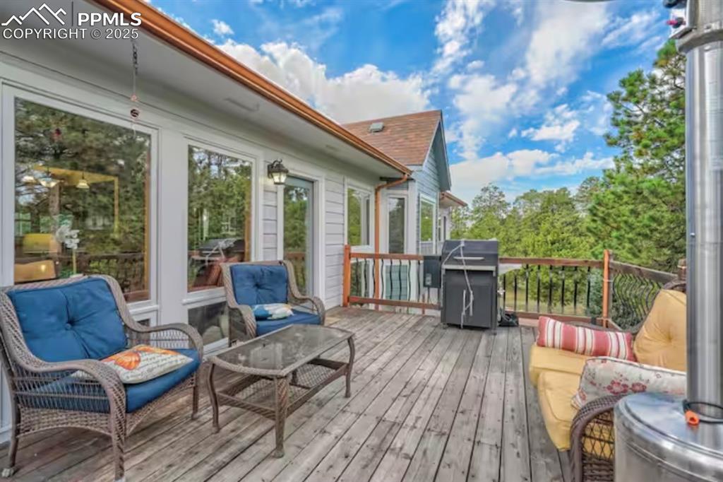Image 38 of 48: Wooden deck with area for grilling and outdoor lounge area