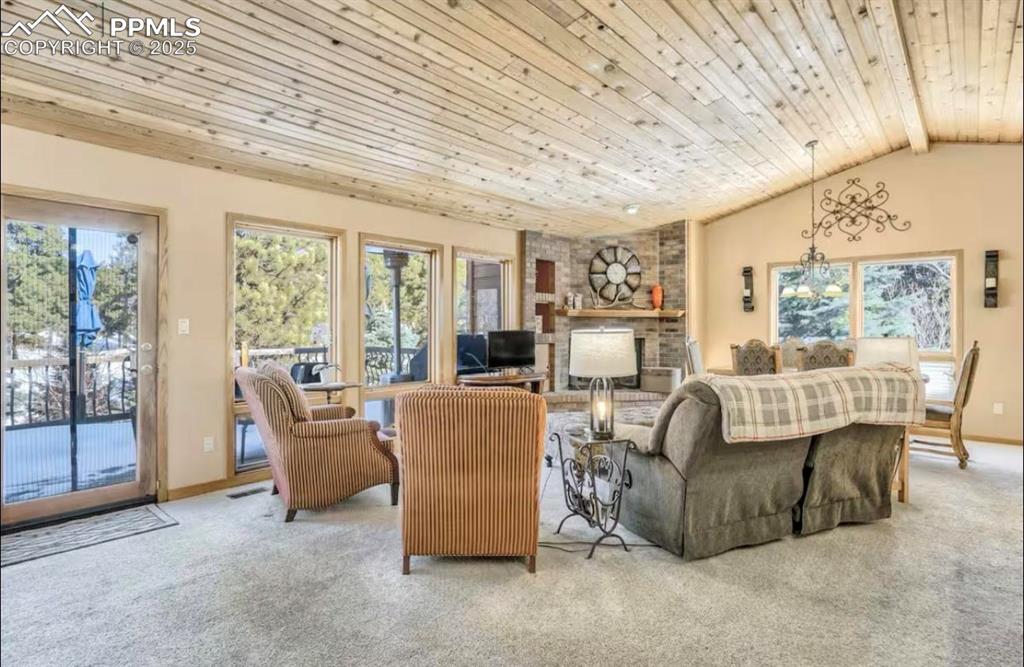 Image 4 of 48: Carpeted living room with wooden ceiling, lofted ceiling, and a fireplace