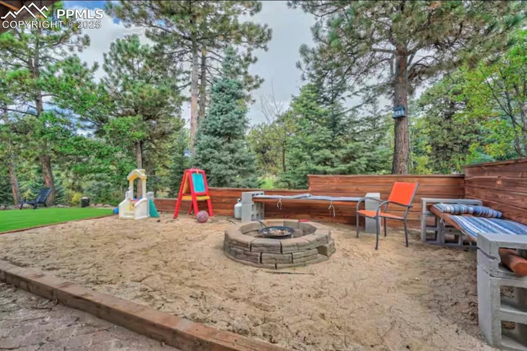 Image 44 of 48: View of patio featuring an outdoor fire pit and a playground