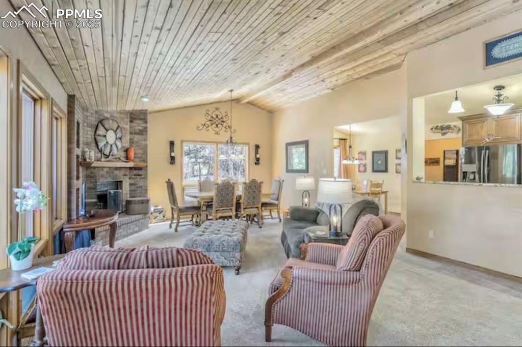 Image 5 of 48: Living area featuring vaulted ceiling, wooden ceiling, carpet floors, and a