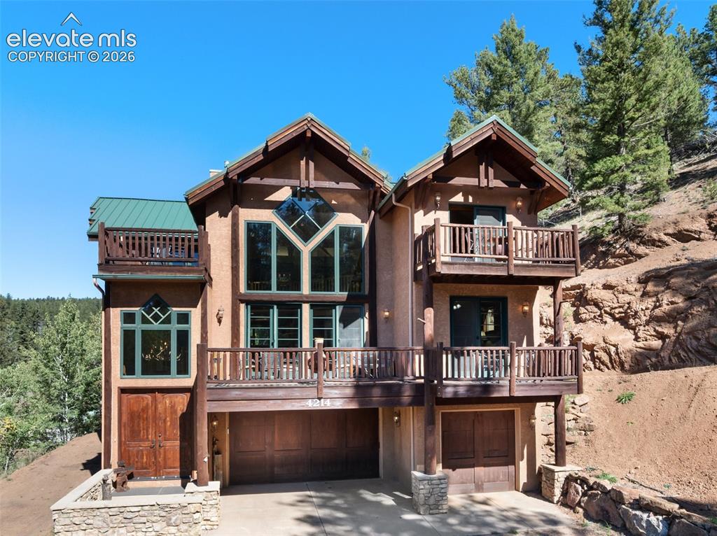 Image 2 of 50: Multi-level stucco exterior with wood accents, multiple balconies, a covere