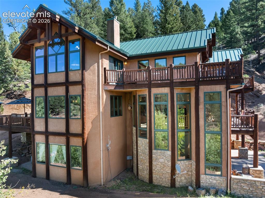 Image 3 of 50: Multi-level stucco exterior with timber framing, stone accents, and an exte