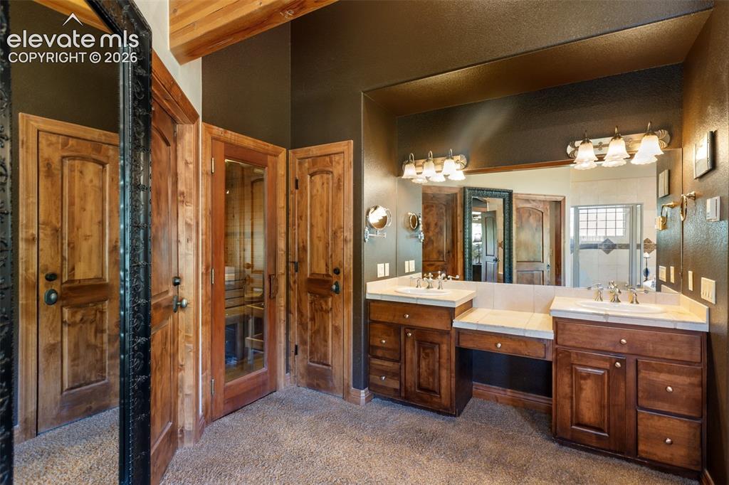 Image 38 of 50: Glass door entry to the dry sauna located in the primary bathroom.