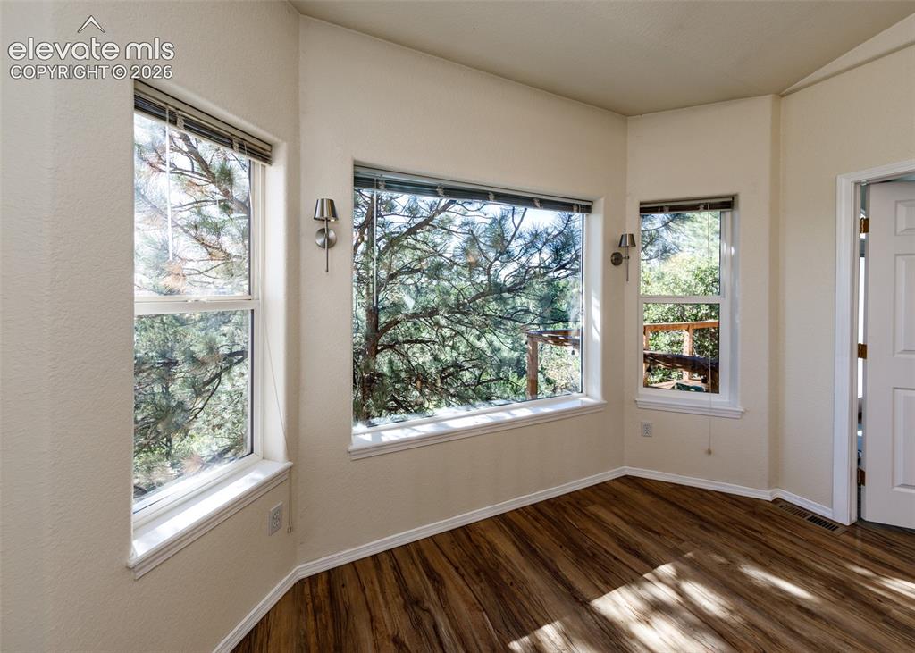 Image 10 of 48: Bay window configuration with three-pane glazing, wood-finish flooring, and