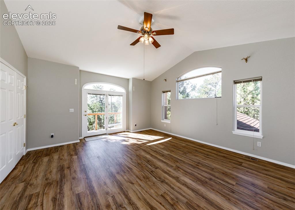 Image 11 of 48: Vaulted ceiling with a centrally mounted lighted ceiling fan, wood-finish f