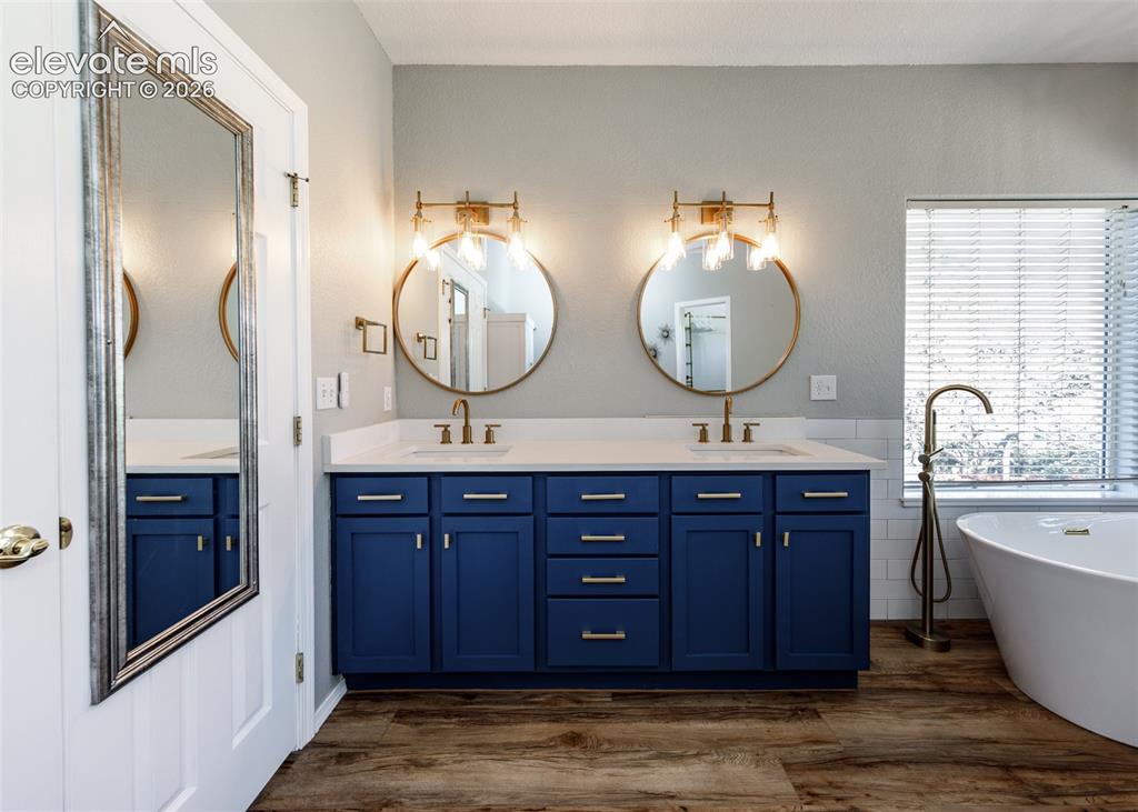 Image 15 of 48: Double vanity featuring deep blue cabinetry, quartz countertops, dual circu