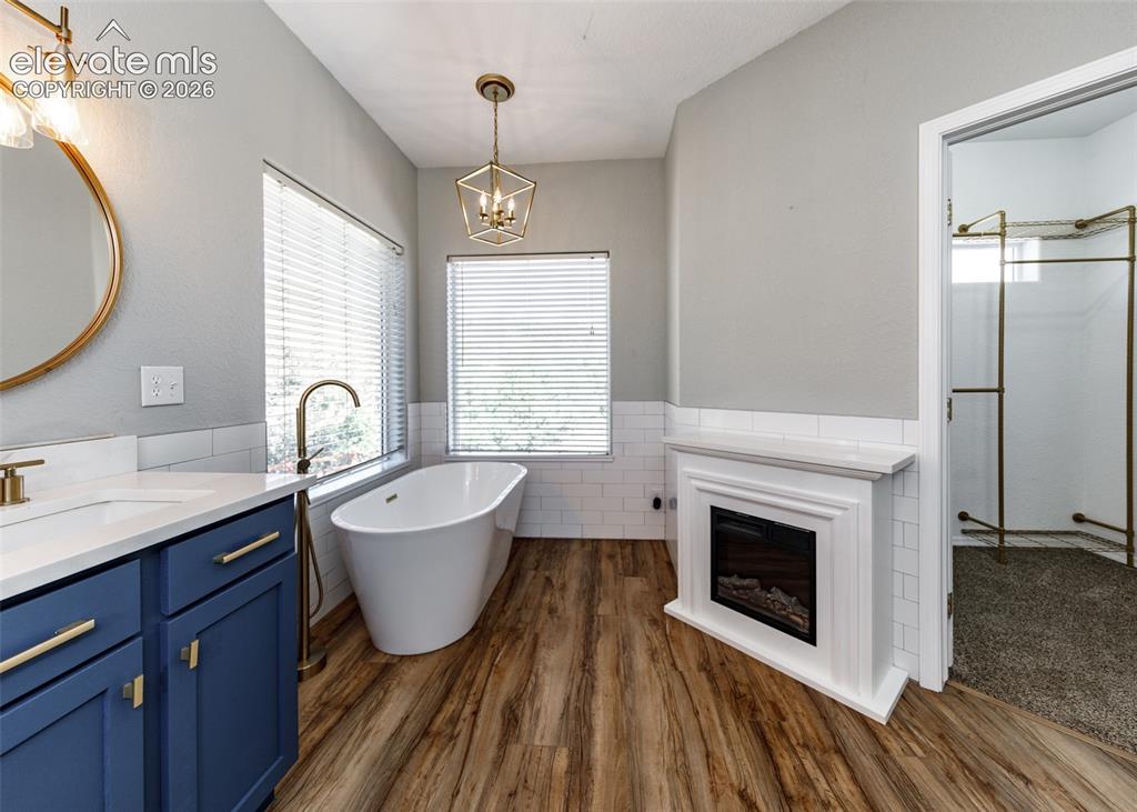 Image 16 of 48: Freestanding soaking tub with a floor-mounted faucet, wood-finish flooring,