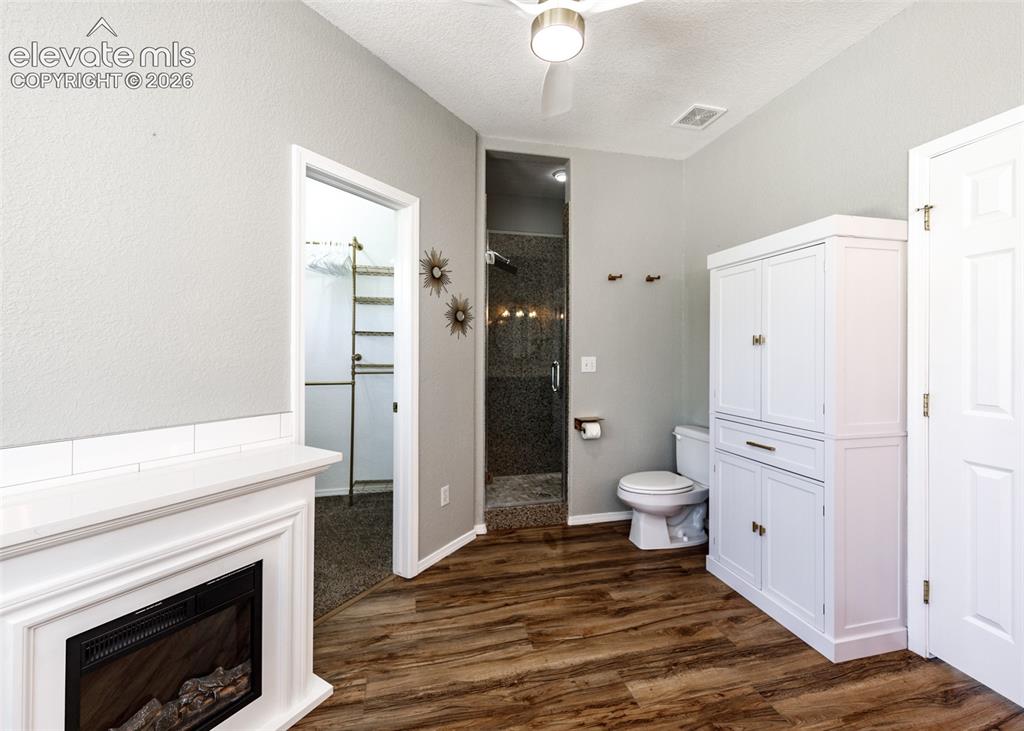 Image 17 of 48: Electric fireplace with white mantle, wood-finish flooring, built-in white
