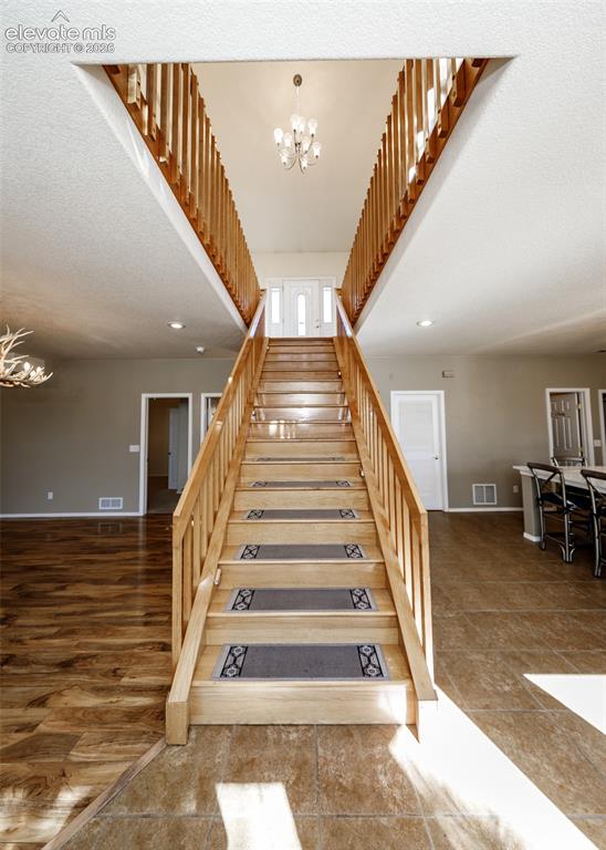 Image 24 of 48: Grand foyer featuring a split staircase with wood railings, vaulted ceiling
