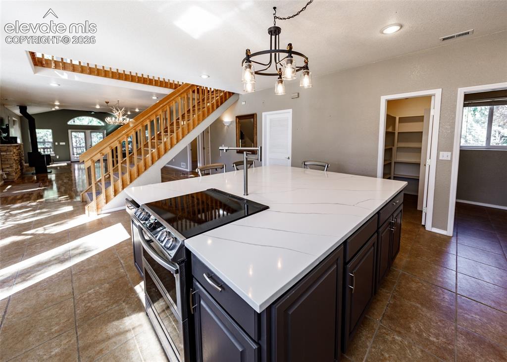 Image 25 of 48: Kitchen island featuring a white surface with grey veining, dark-toned cabi