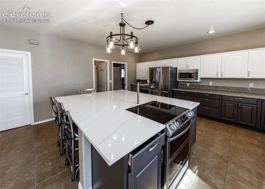 Image 26 of 48: Kitchen featuring a large central island with a stone-composite countertop,
