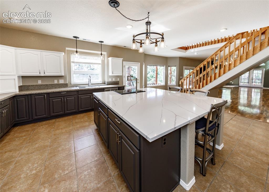 Image 27 of 48: Kitchen featuring a large central island with white stone-finish countertop