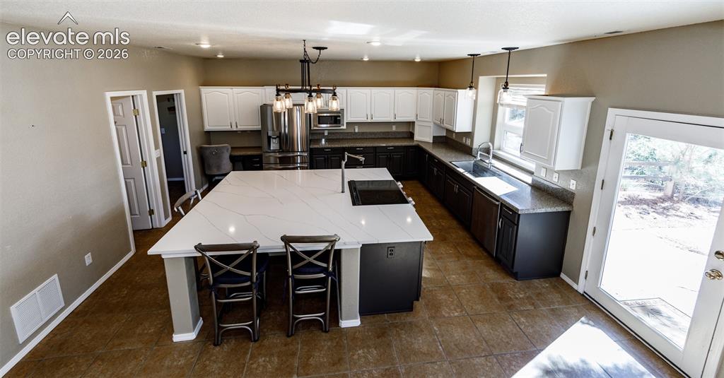 Image 29 of 48: Kitchen featuring a large central island with light stone-patterned counter