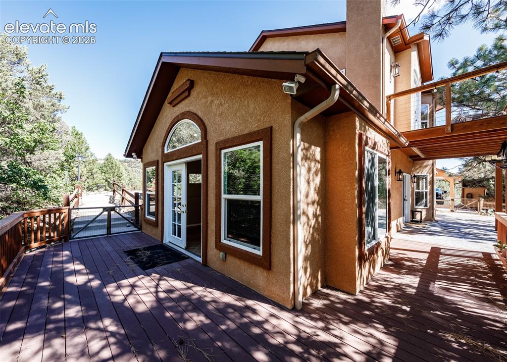 Image 41 of 48: Stucco exterior with multi-level wooden decking, arched transom window, gla