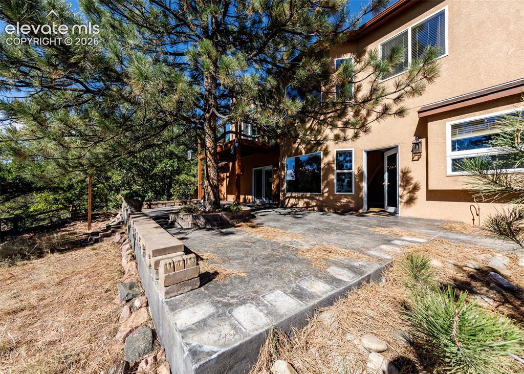 Image 42 of 48: Stucco exterior featuring an expansive concrete patio with integrated tiere