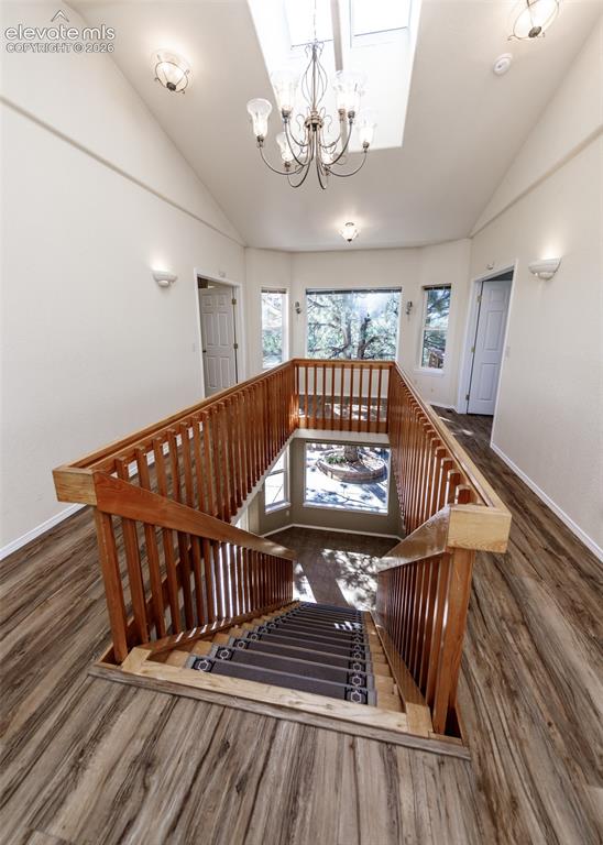 Image 9 of 48: Vaulted ceilings featuring a skylight, wood-finish flooring, wood railing, 