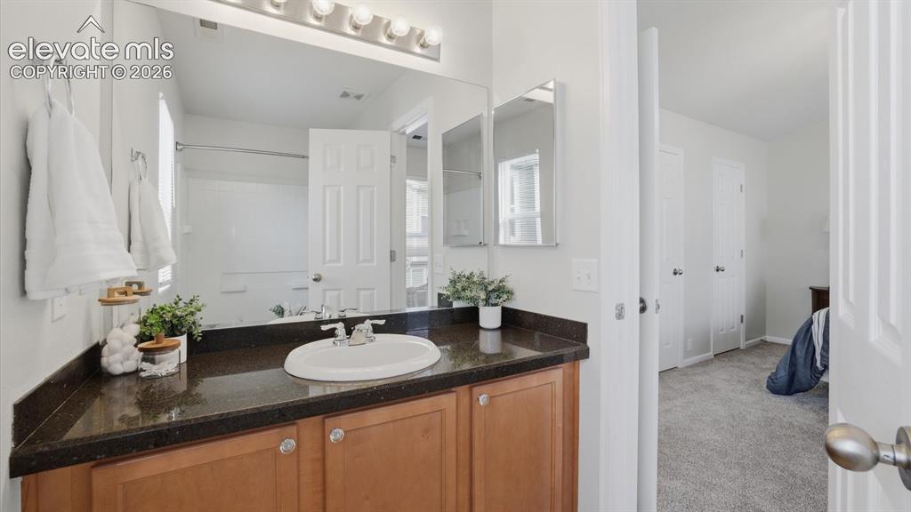 Image 22 of 29: Upper Level Primary Bathroom with vanity, mirror, and tiled tub/shower.