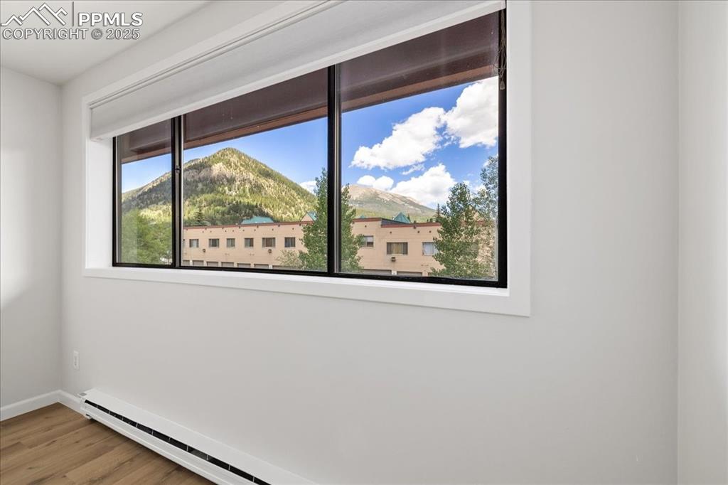 Image 3 of 17: Unfurnished room with baseboard heating, wood finished floors, and a mounta