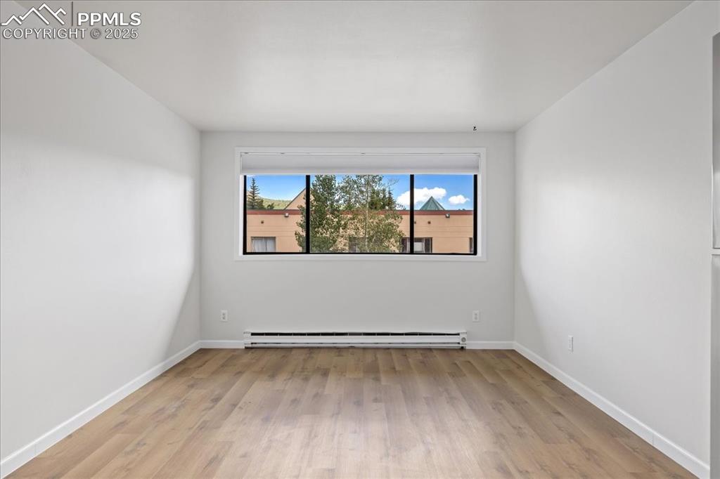 Image 4 of 17: Spare room featuring light wood finished floors and a baseboard radiator