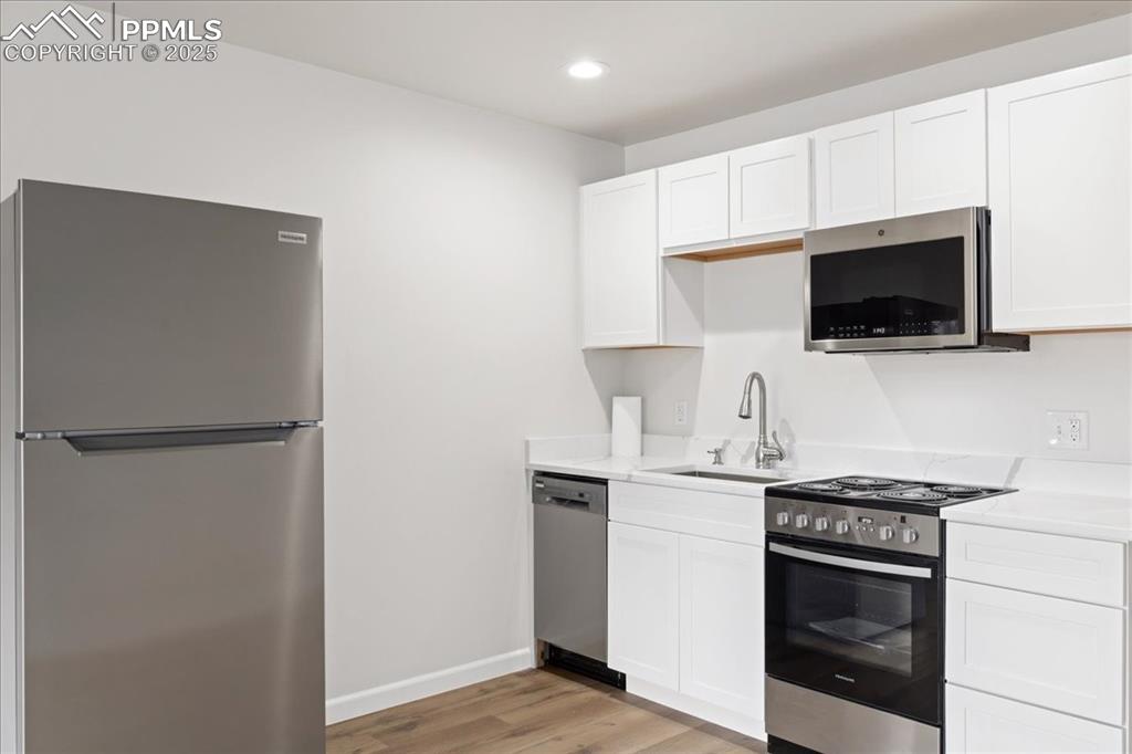 Image 6 of 17: Kitchen with stainless steel appliances, light wood-type flooring, light co