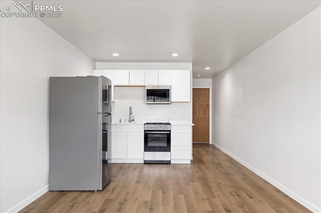 Image 7 of 17: Kitchen featuring appliances with stainless steel finishes, white cabinets,