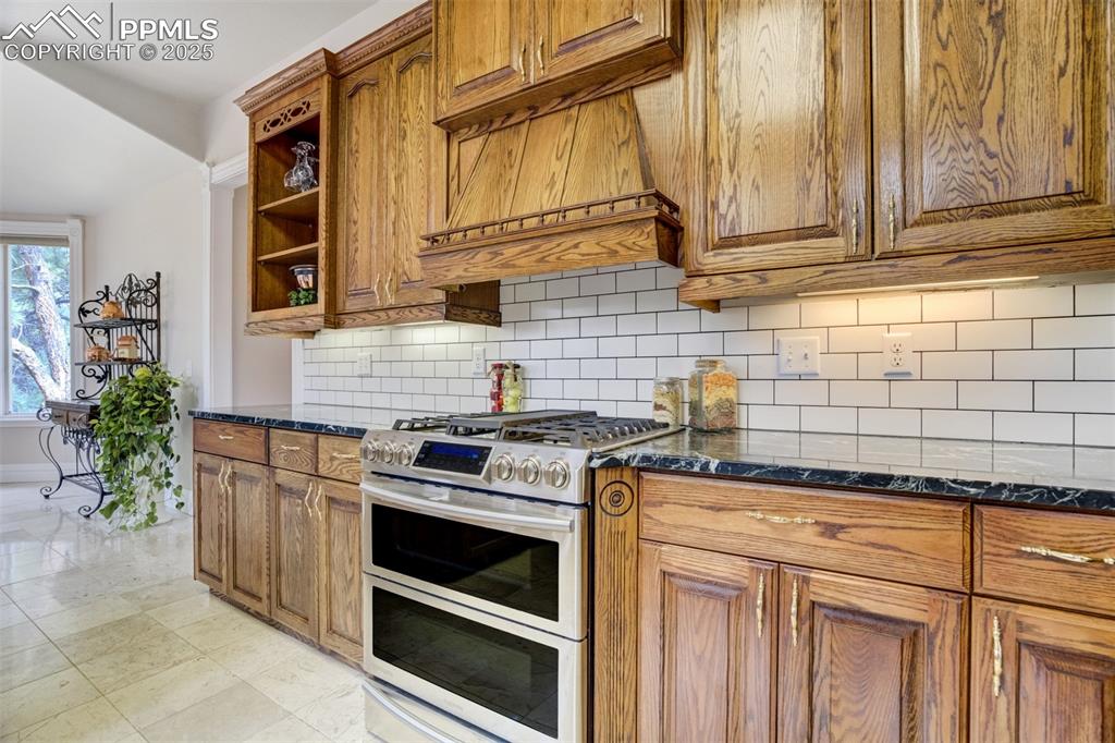 Image 12 of 50: Kitchen featuring double oven range, open shelves, brown cabinetry, and soa