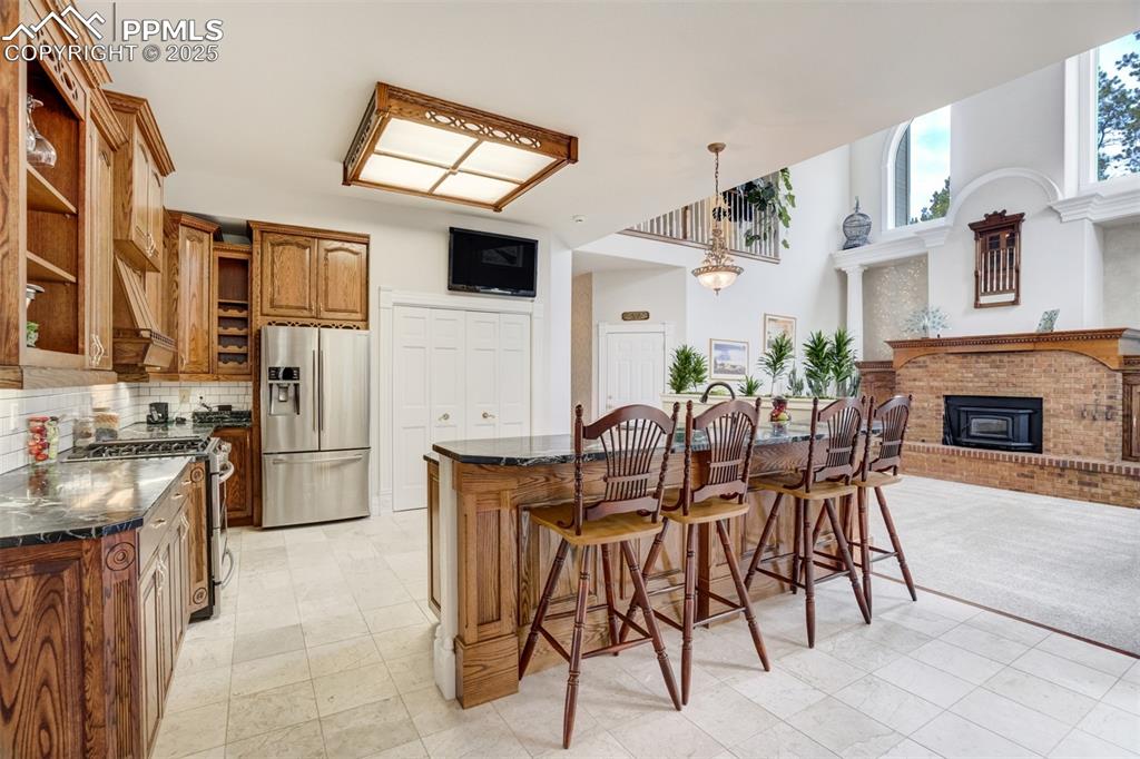 Image 15 of 50: Kitchen featuring a breakfast bar, appliances with stainless steel finishes