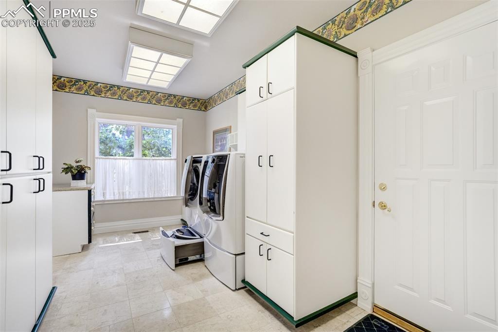 Image 20 of 50: Laundry offers custom built-in cabinets and state-of-the-art washer and dry