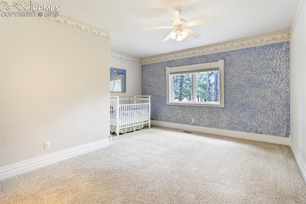 Image 29 of 50: Bedroom featuring carpet flooring, wallpapered walls, and a ceiling fan