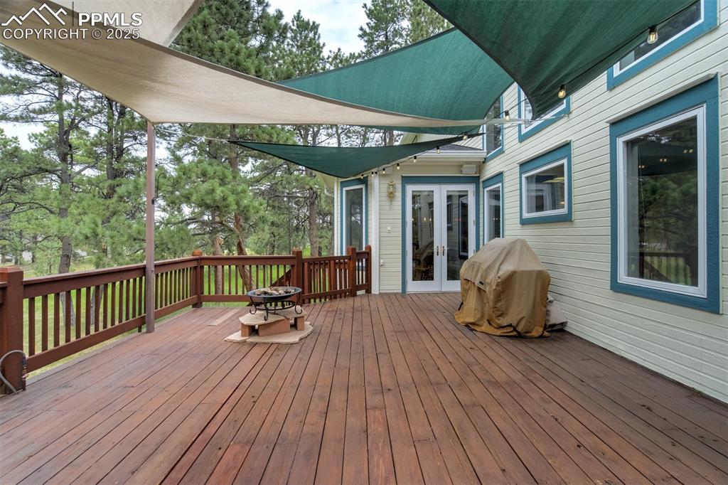 Image 37 of 50: Wooden deck with french doors and area for grilling and entertaining. Sail 
