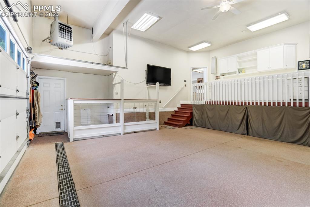 Image 40 of 50: Garage is equipped with a dog kennel area and television.