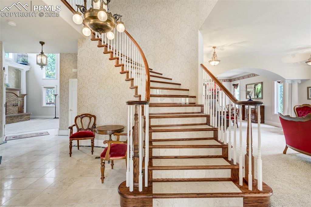 Image 6 of 50: Sweeping curved staircase in marble and wood