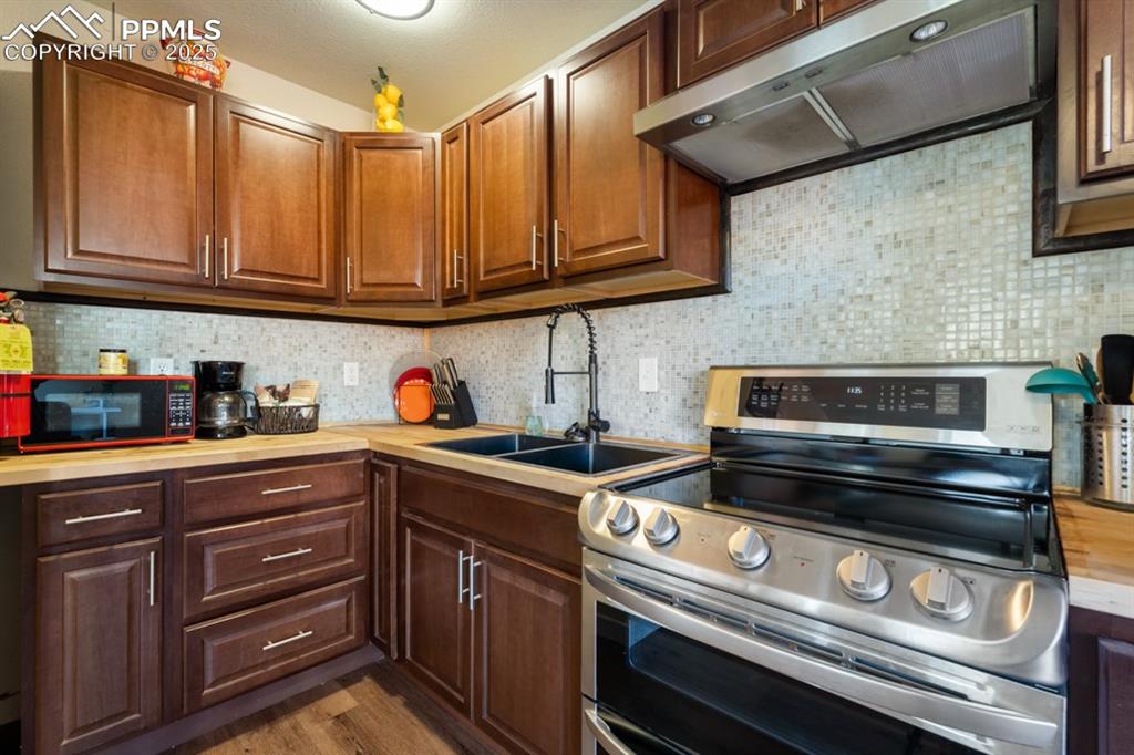 Image 6 of 19: Kitchen featuring double oven range, backsplash, under cabinet range hood,