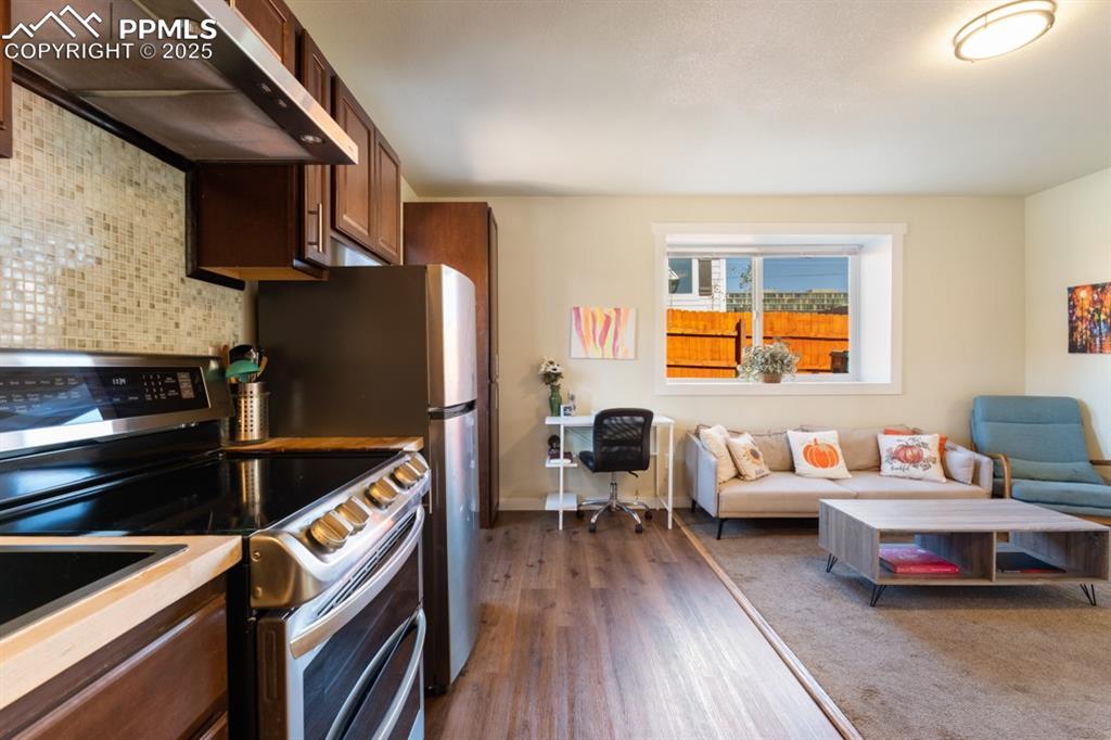 Image 7 of 19: Kitchen with double oven range, under cabinet range hood, wood finished flo