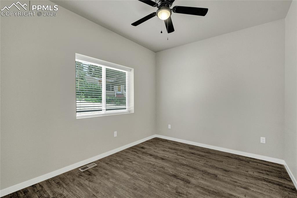 Image 11 of 38: Spare room featuring dark wood-style floors and a ceiling fan
