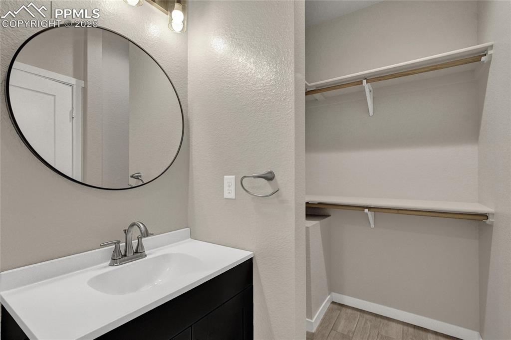 Image 14 of 38: Bathroom featuring vanity, a spacious closet, light wood-type flooring, and
