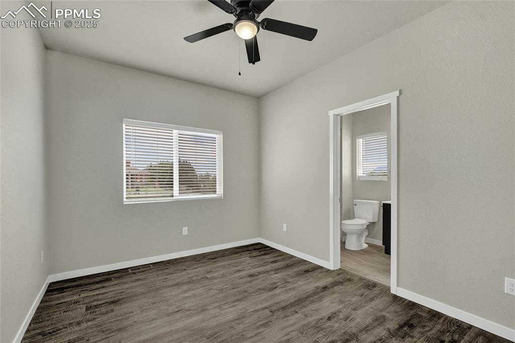 Image 15 of 38: Bedroom featuring dark wood-style floors, ceiling fan, and ensuite bathroom