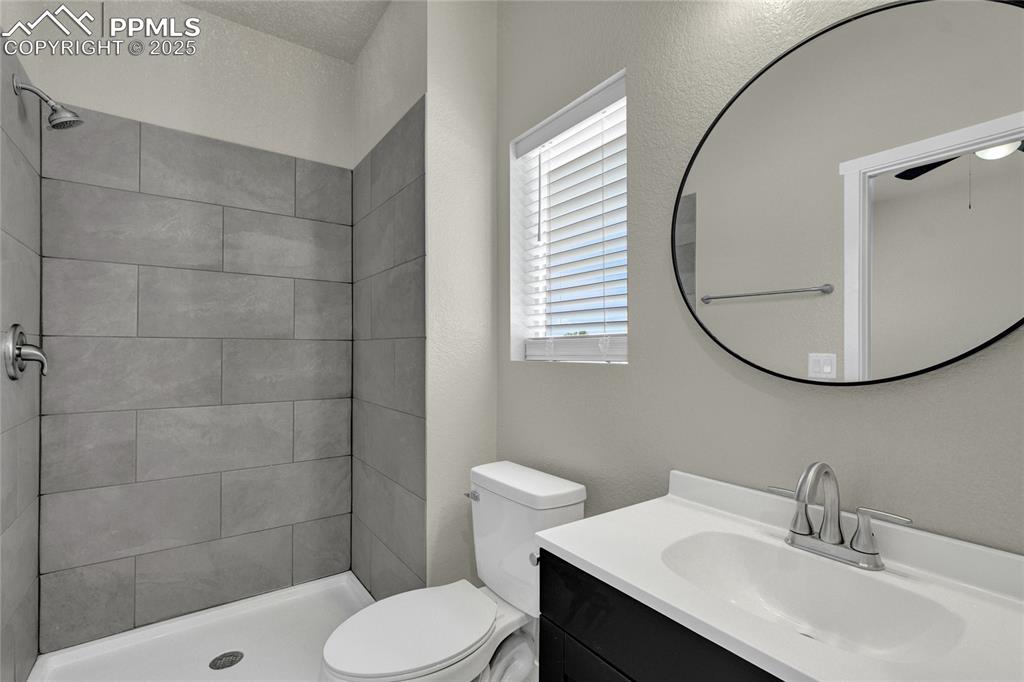 Image 17 of 38: Full bath featuring vanity, a shower stall, and a textured wall