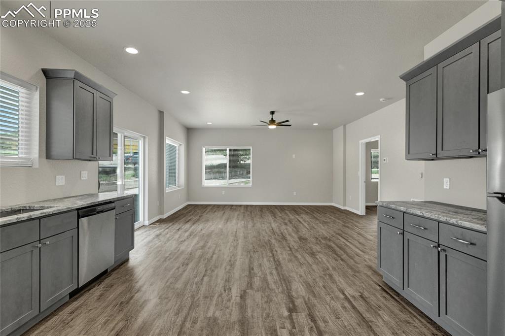 Image 2 of 38: Kitchen with gray cabinetry, light stone countertops, appliances with stain