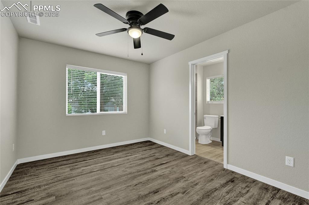Image 23 of 38: Bedroom with a ceiling fan, dark wood finished floors, and connected bathro