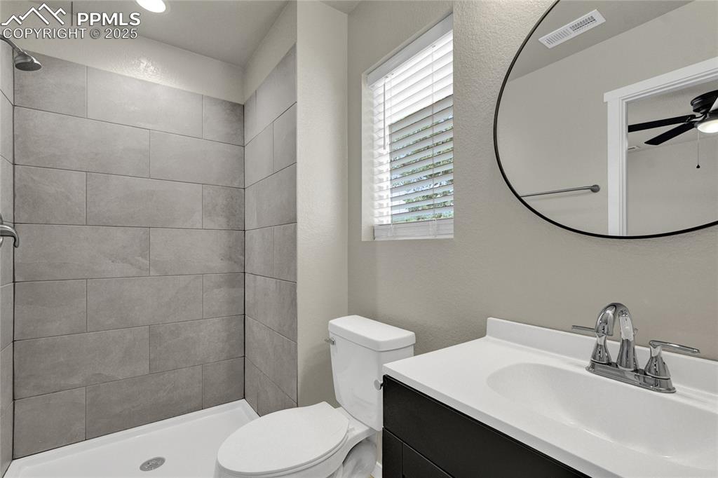 Image 25 of 38: Full bath featuring vanity, a shower stall, ceiling fan, and a textured wal