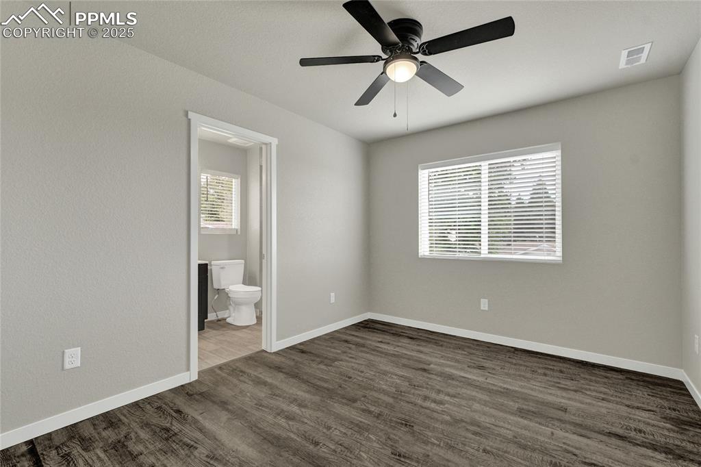 Image 28 of 38: Bedroom with dark wood-style floors, a ceiling fan, multiple windows, and e