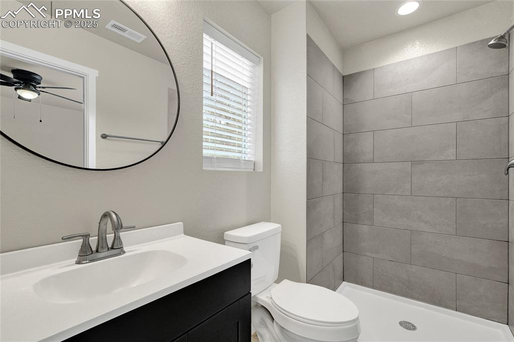 Image 30 of 38: Full bathroom with vanity, a shower stall, ceiling fan, and a textured wall