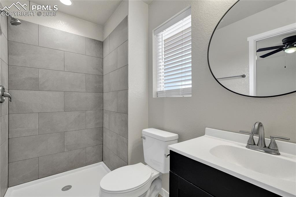 Image 34 of 38: Bathroom featuring vanity, a shower stall, ceiling fan, and a textured wall