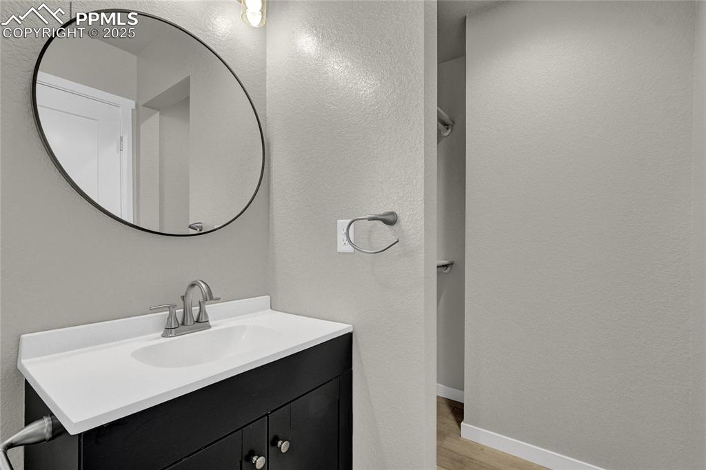 Image 35 of 38: Bathroom with a textured wall, vanity, and light wood finished floors