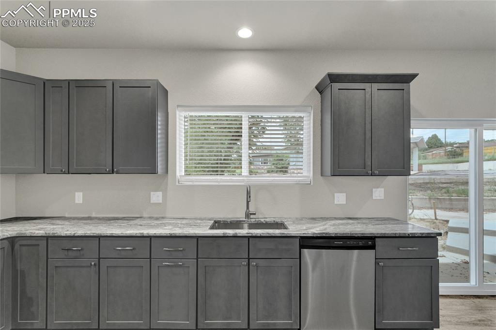 Image 5 of 38: Kitchen with light stone countertops, dishwasher, gray cabinets, and recess