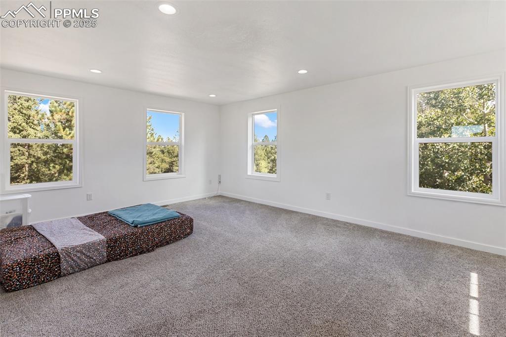 Image 33 of 44: Upper level nonconforming bedroom with multiple windows. Could serve as liv